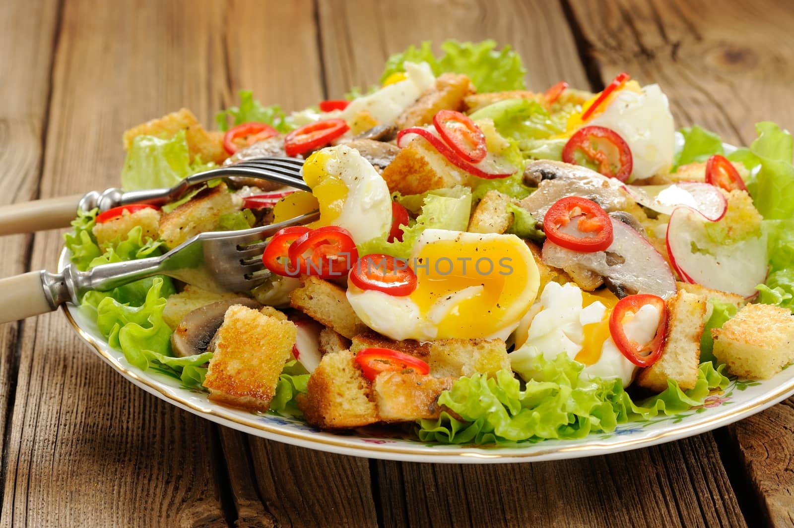 Salad Caesar with mushrooms, eggs, chili and radish with two forks on wooden background horizontal