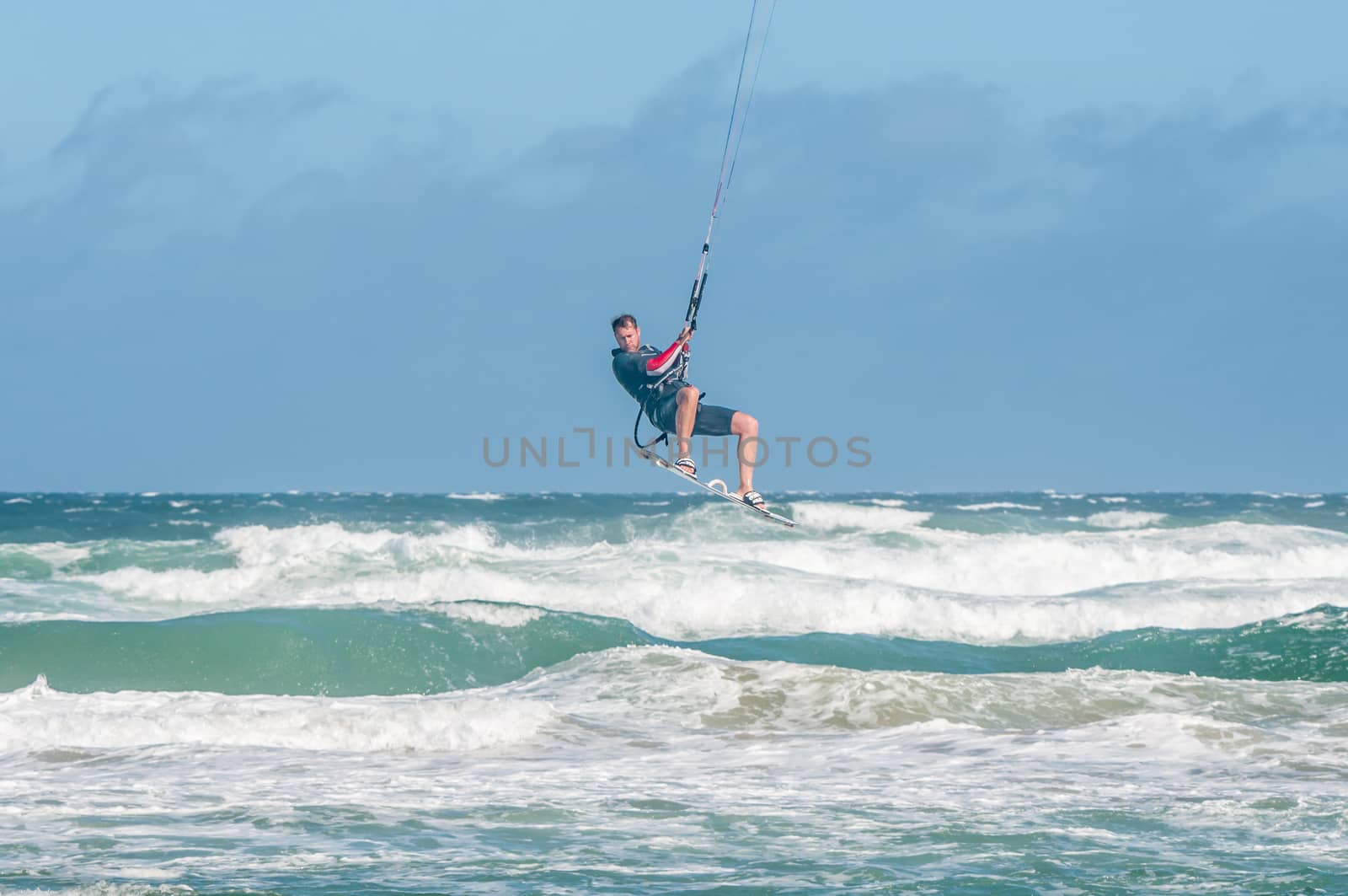 MOSSELBAY, SOUTH AFRICA - DECEMBER 31, 2014: A stormwind lifts an unidentified windsurfer high above the waves at the Klein Brakrivier beach