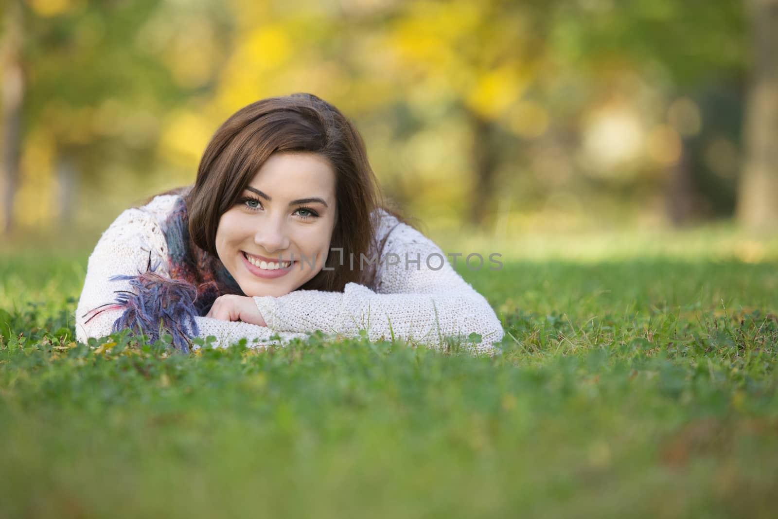 Happy smiling young woman laying down on grass