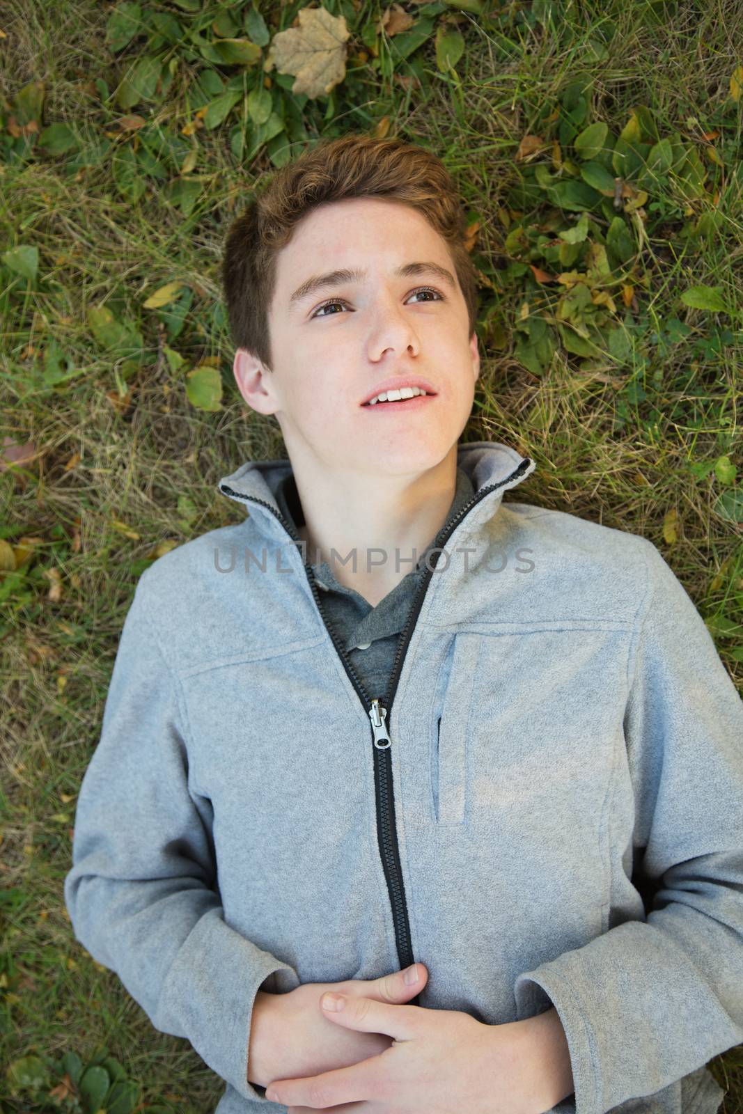 Caucasian teenager laying down on grass looking up