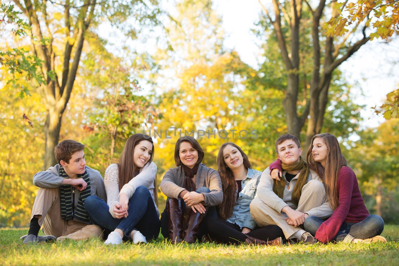 Large group of five teenagers with happy female teacher