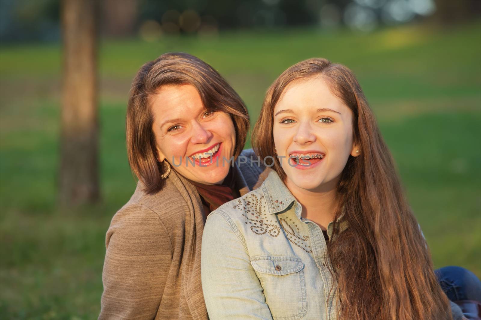 Laughing cute mother and female teenager sitting together