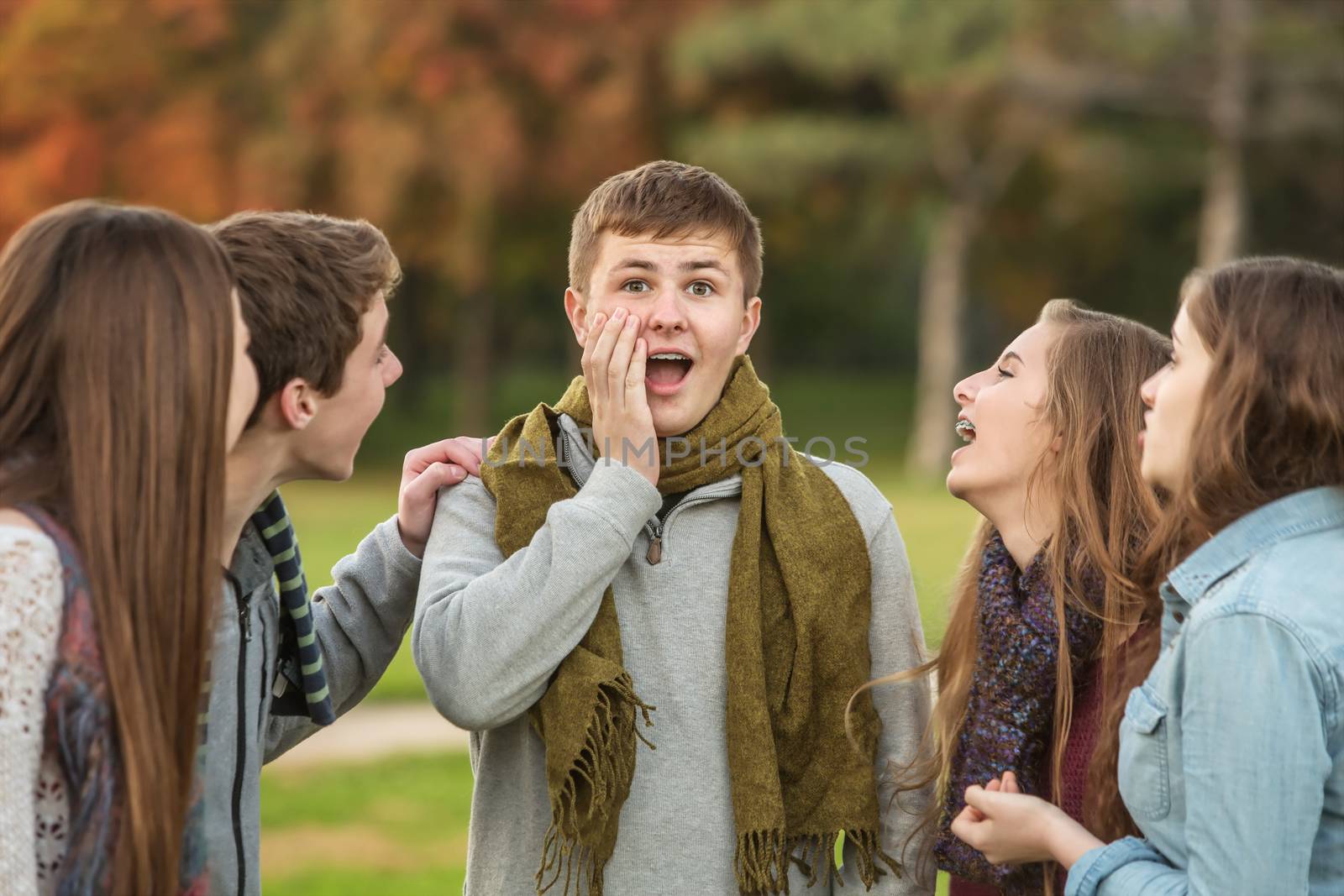 Surprised male teenager with laughing group of friends