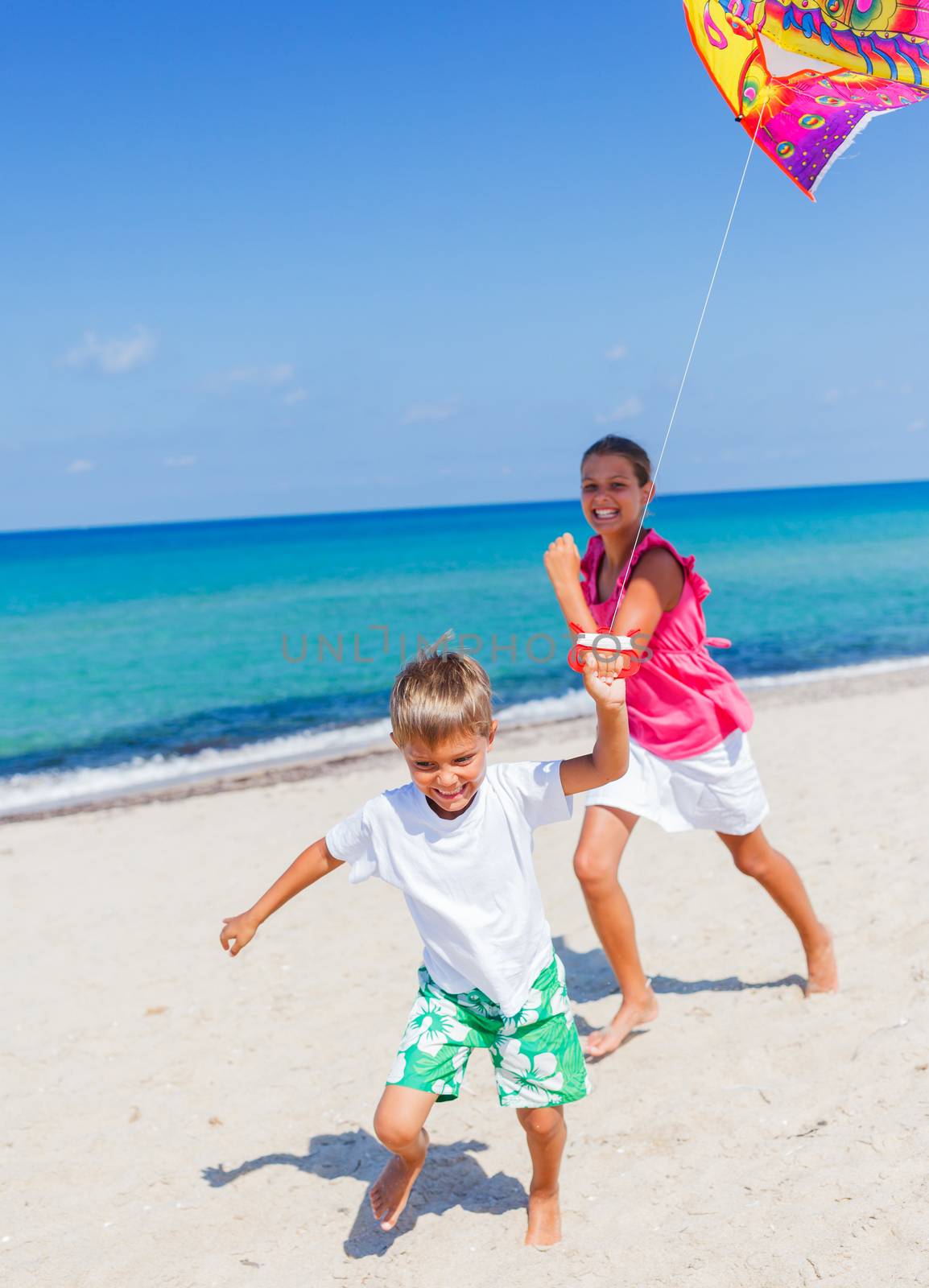 Summer vacation - Cute boy and girl flying kite beach outdoor.