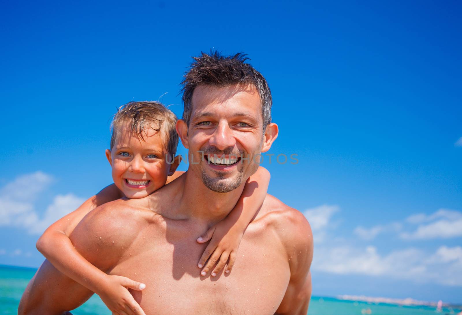 Father holding son on his shoulders at the beach