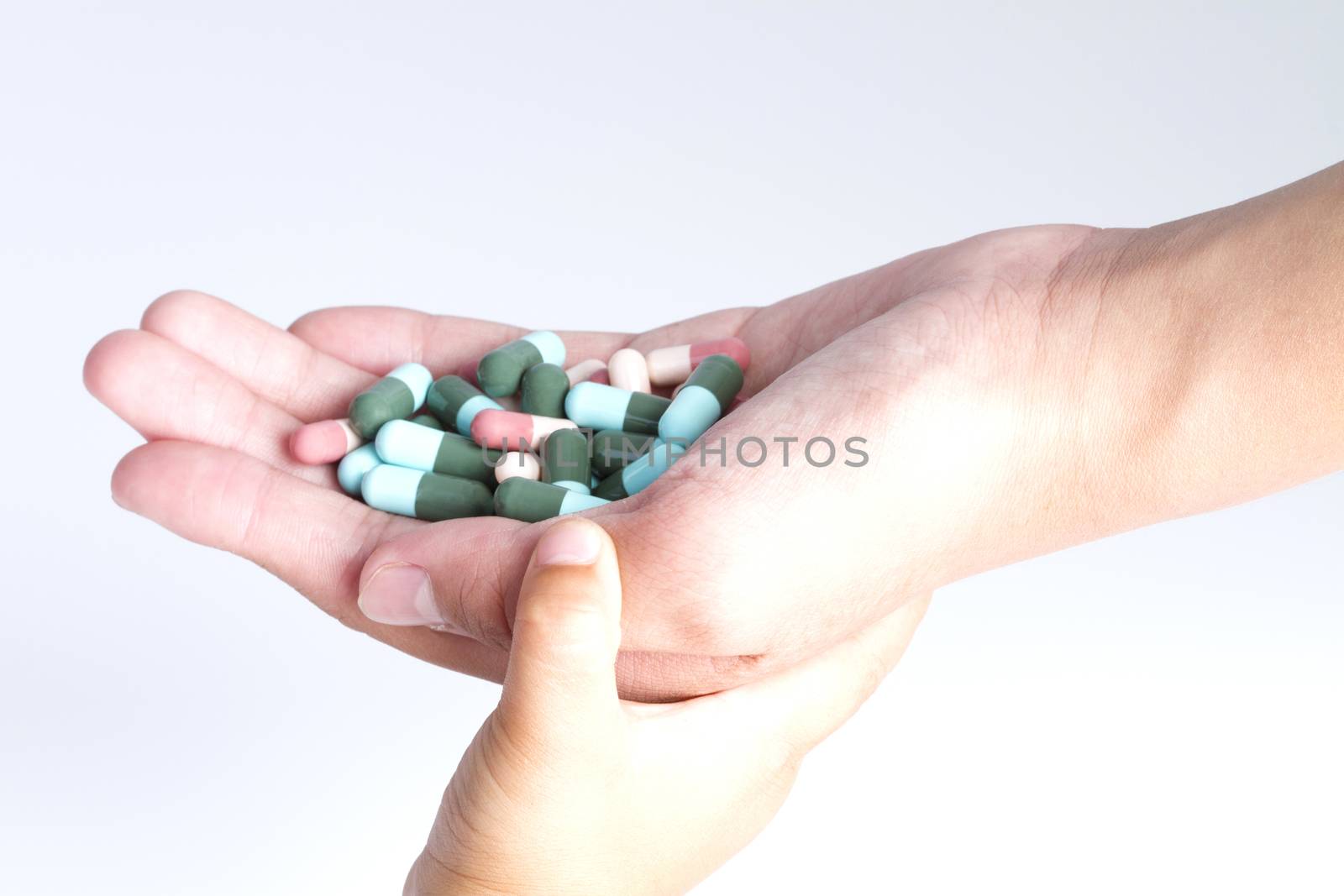 Stack of different pills in the hands over white background