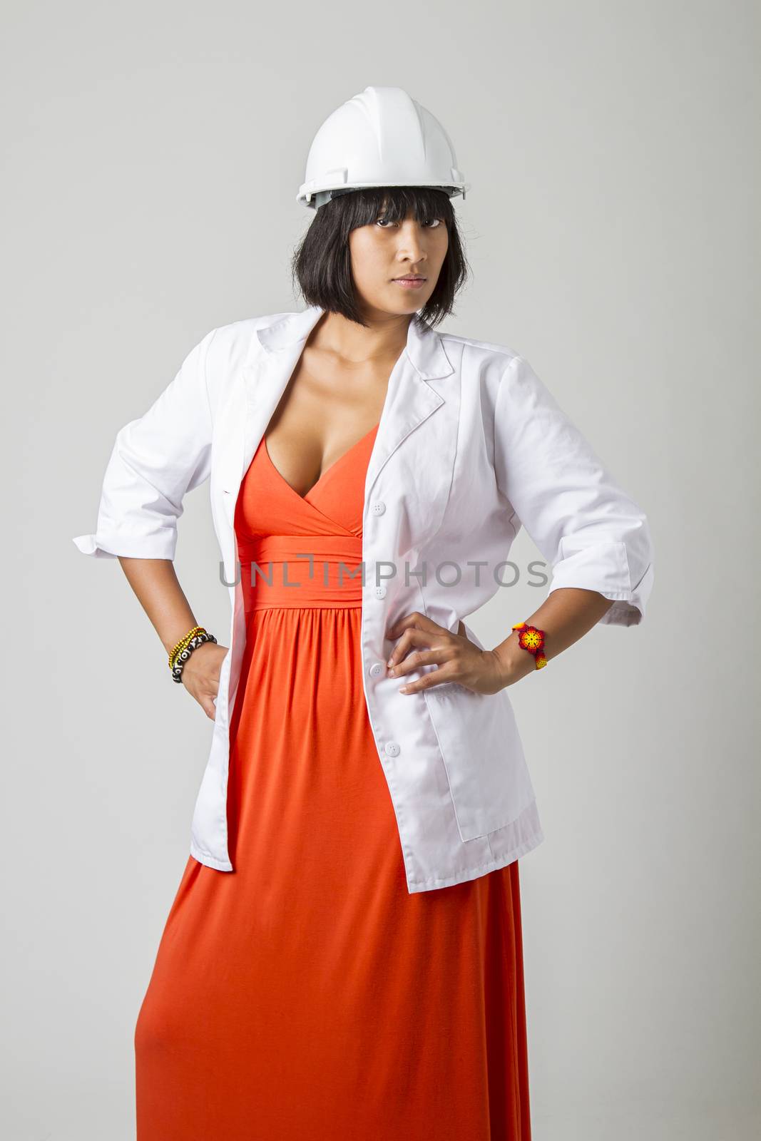 Young sexy philipino engineer, wearing a low cut orange dress, hard hat and a lab coat