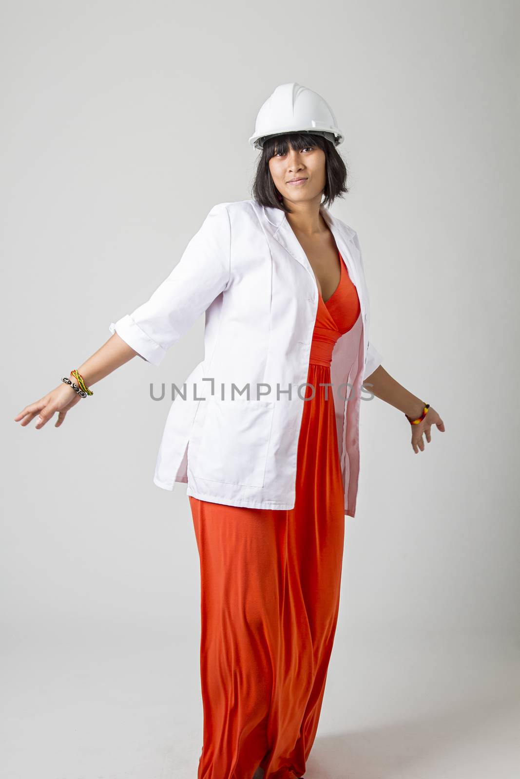 twenty something asian woman wearing a lab coat and a hard hat in the middle of a dance move