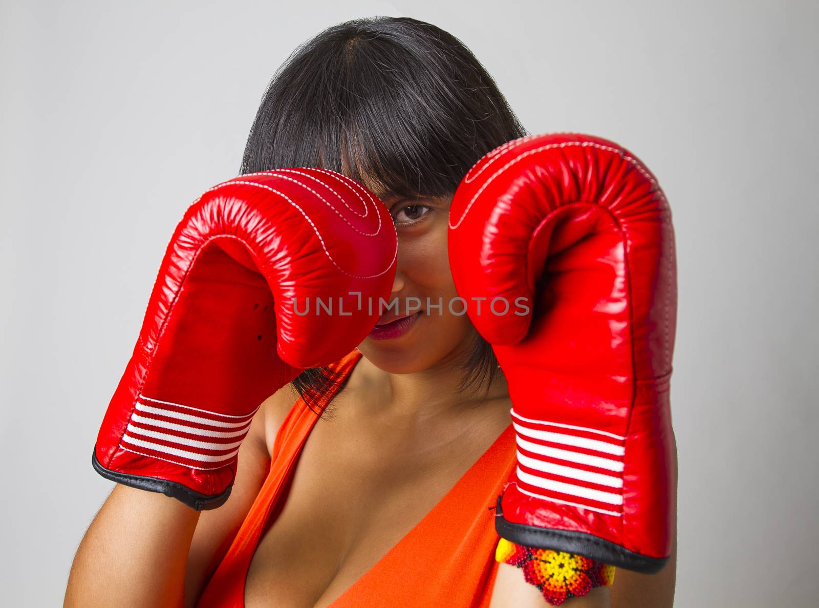 twenty something filipinos woman wearing a low cut orange dress with great smile gearing up for a punch