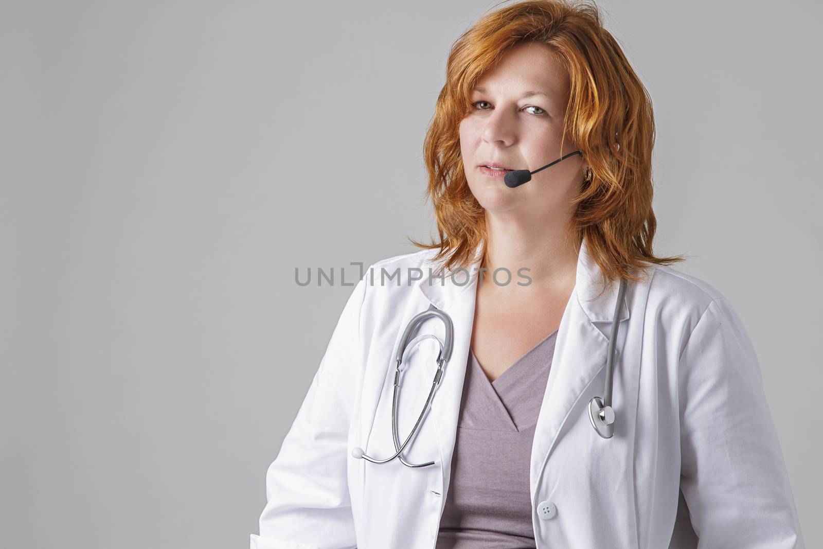 forty something woman doctor with red hair with a stethoscope and a headset