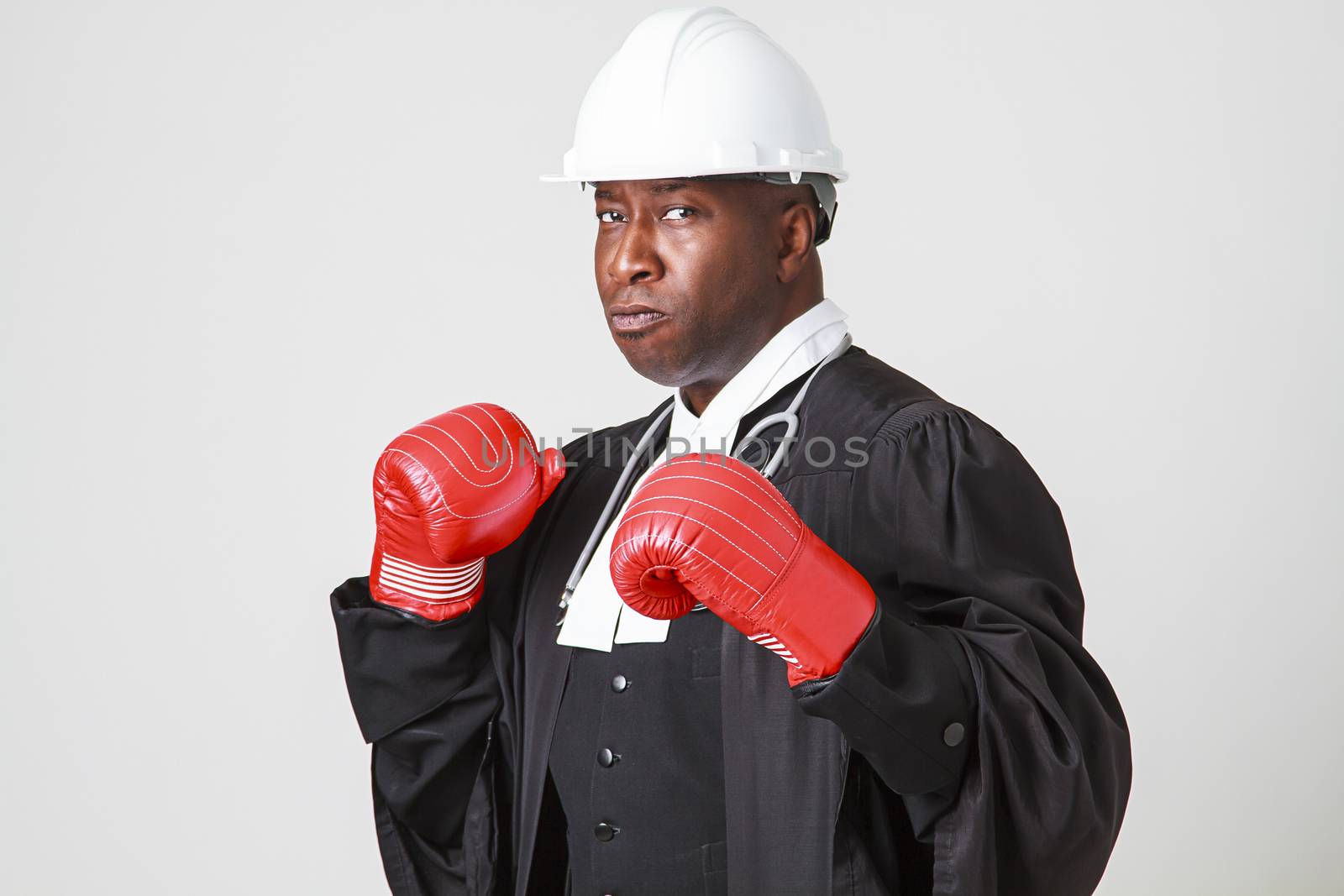 Mid-forties bald black man wearing a canadian lawyer toga, white hard hat, stethoscope and boxing boxing glove