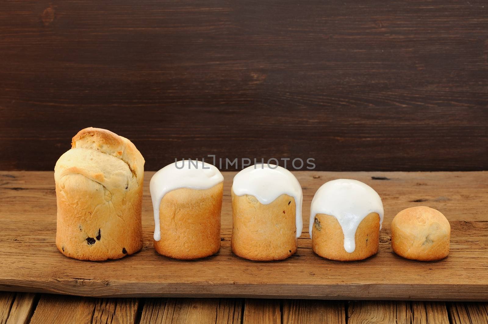 Kulichi, traditional Russian Easter cake with icing on wooden background horizontal with space