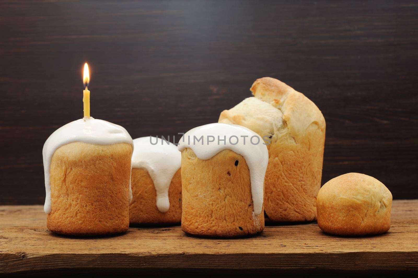 Kulichi, traditional Russian Easter cake with icing and candle on wooden background horizontal