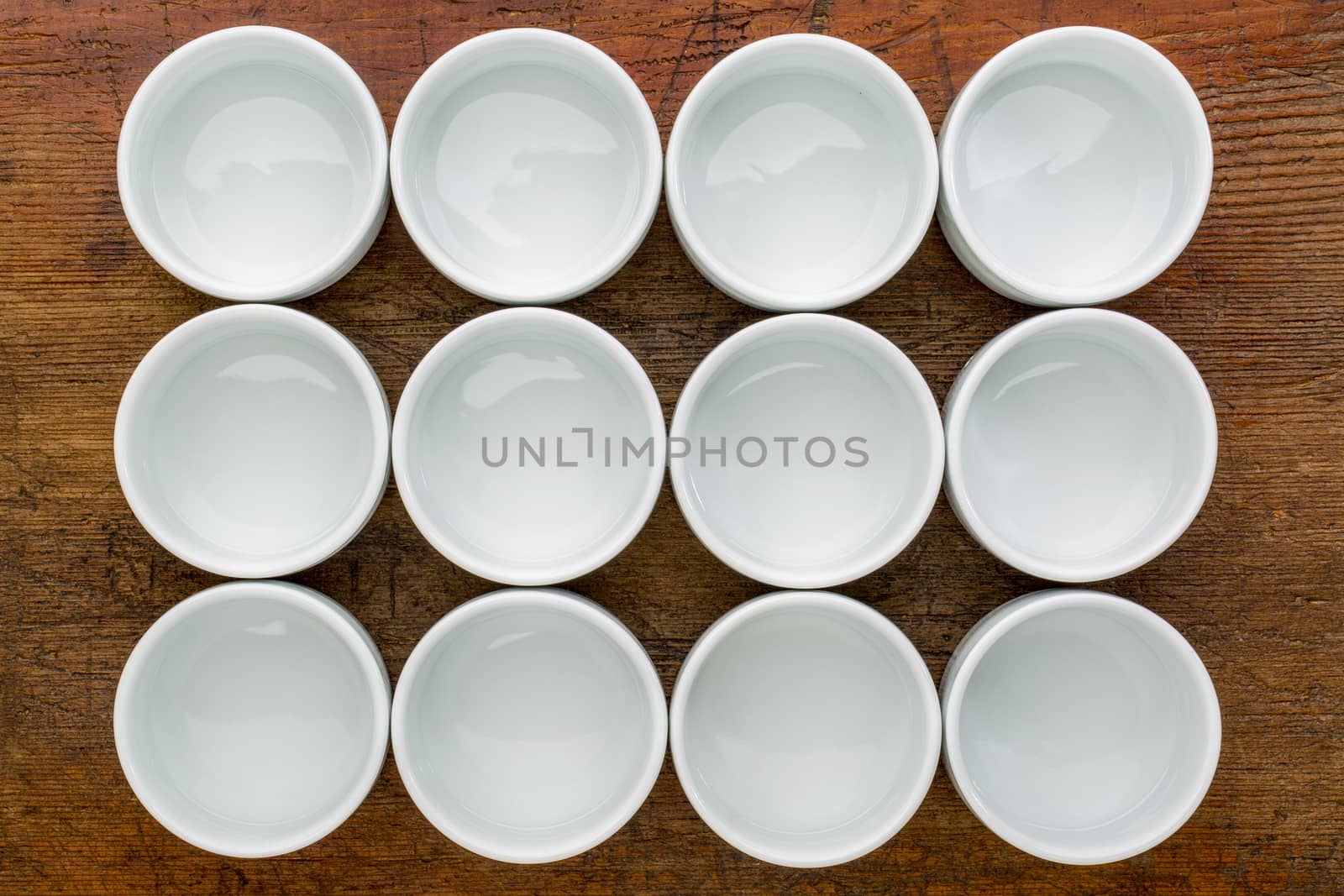 a dozen of empty white ceramic tasting bowls against rustic wood