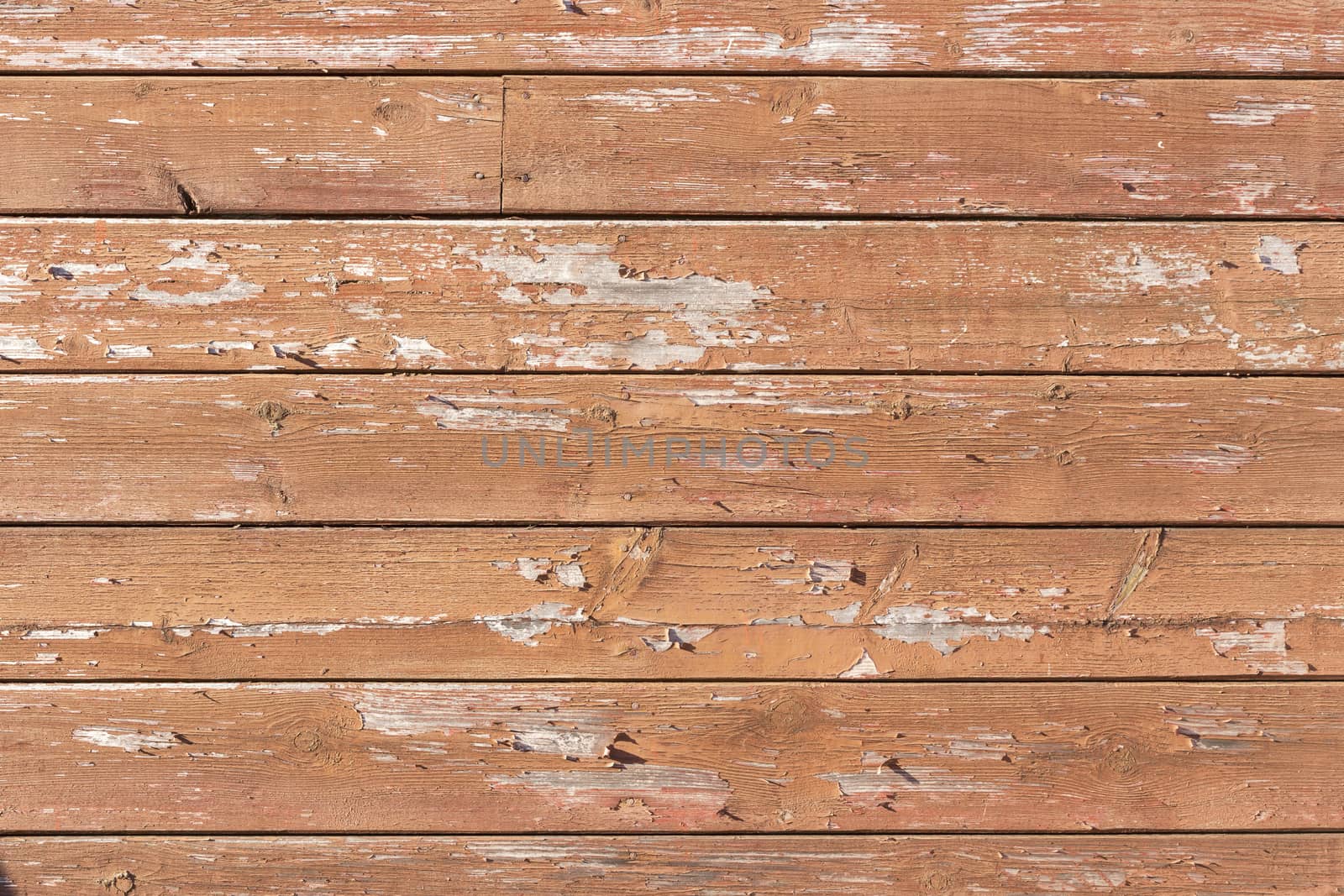 Texture of red paint peeling off boards 