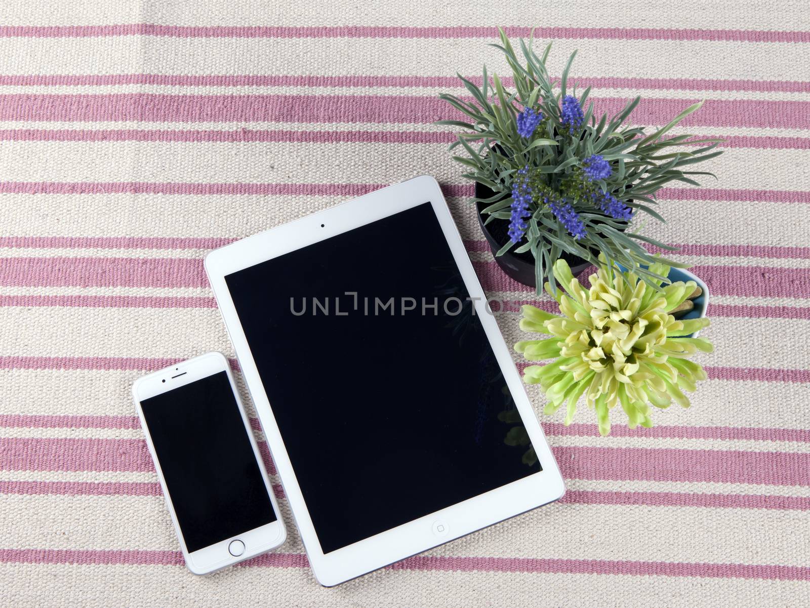 The composition of the tablets on a rustic rug with flowers.