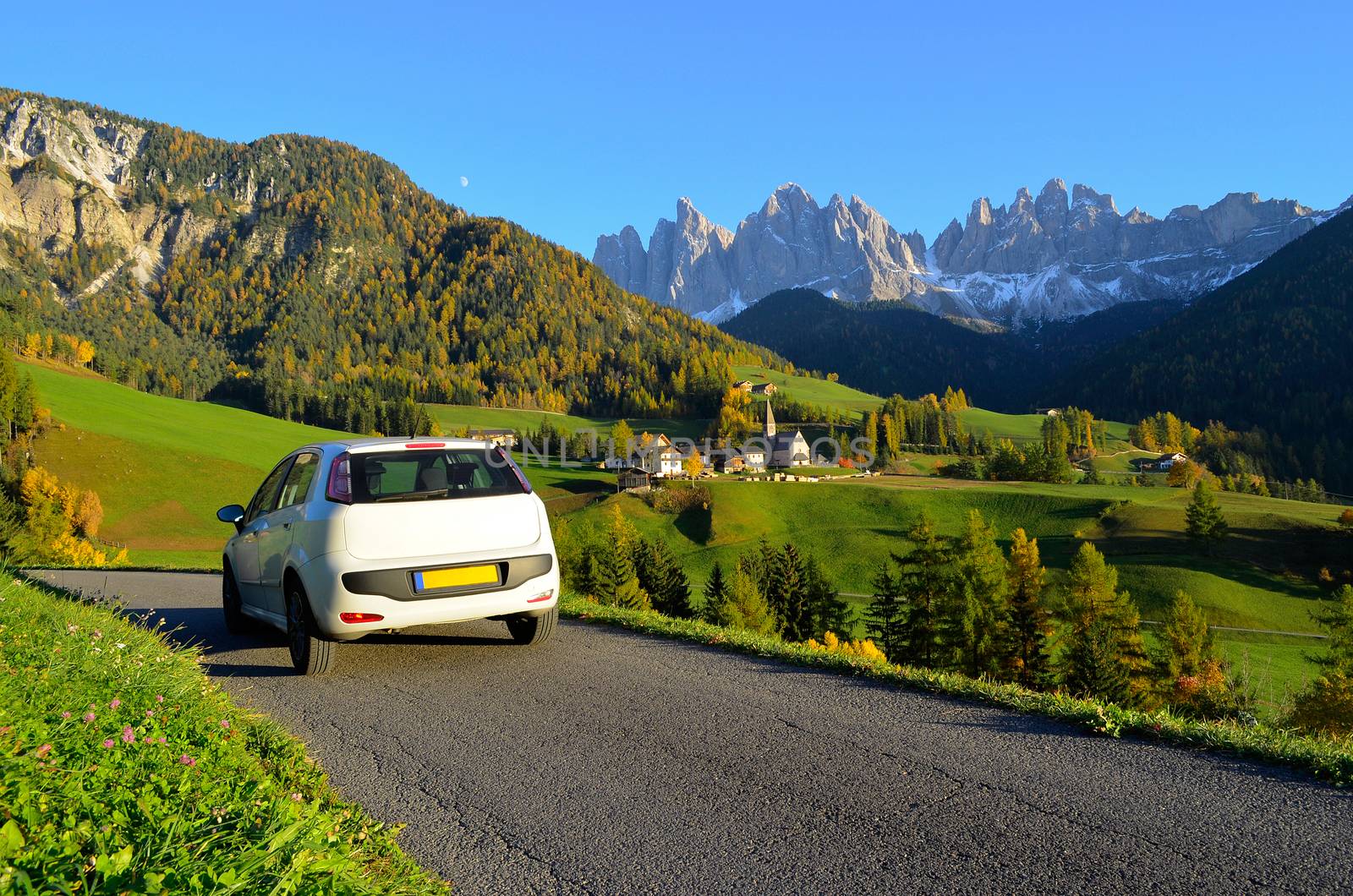 Road trip in a white car in autumn through the Funes valley in Dolomites area in South Tyrol, Italy.
