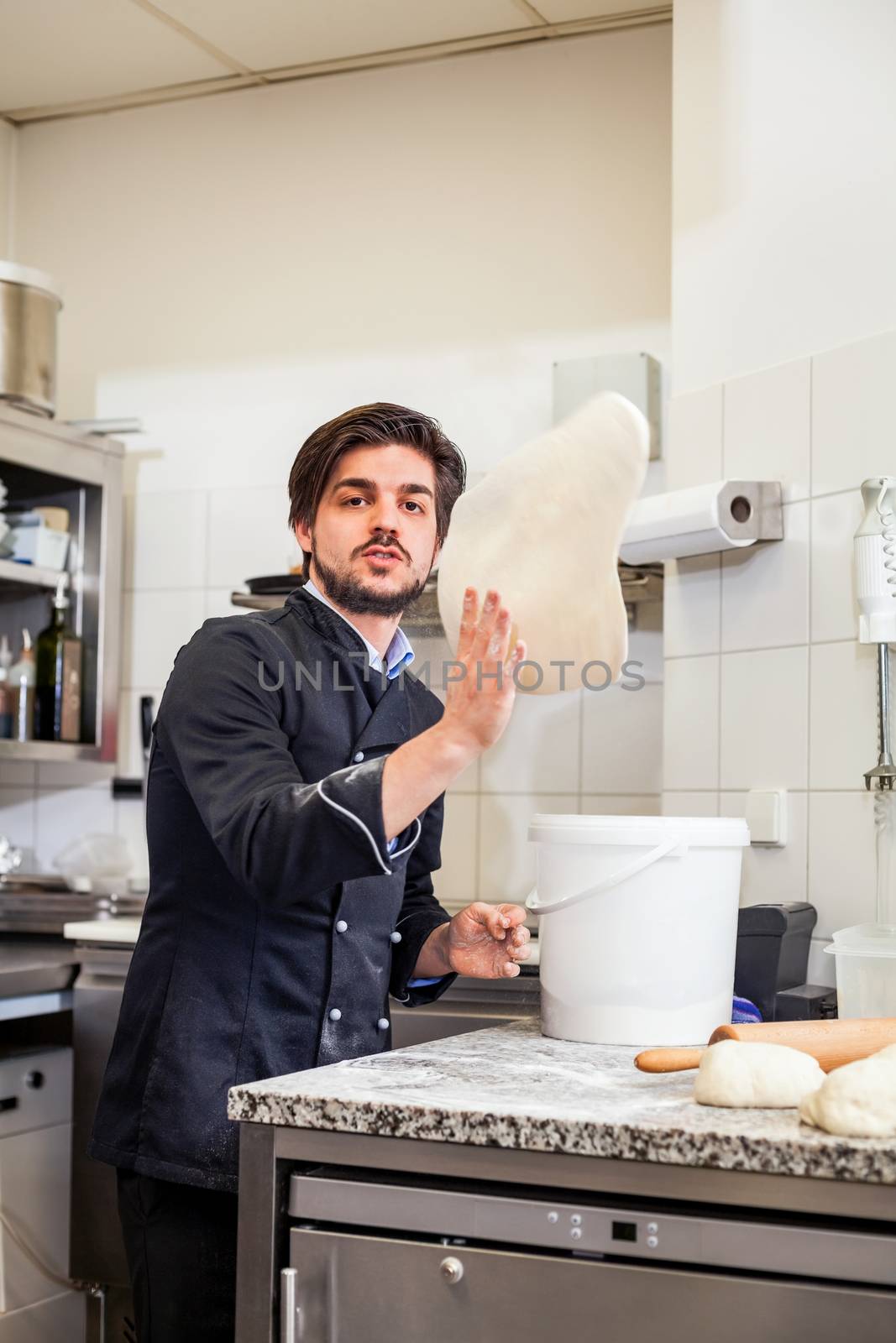 Chef tossing dough while making pastries by juniart