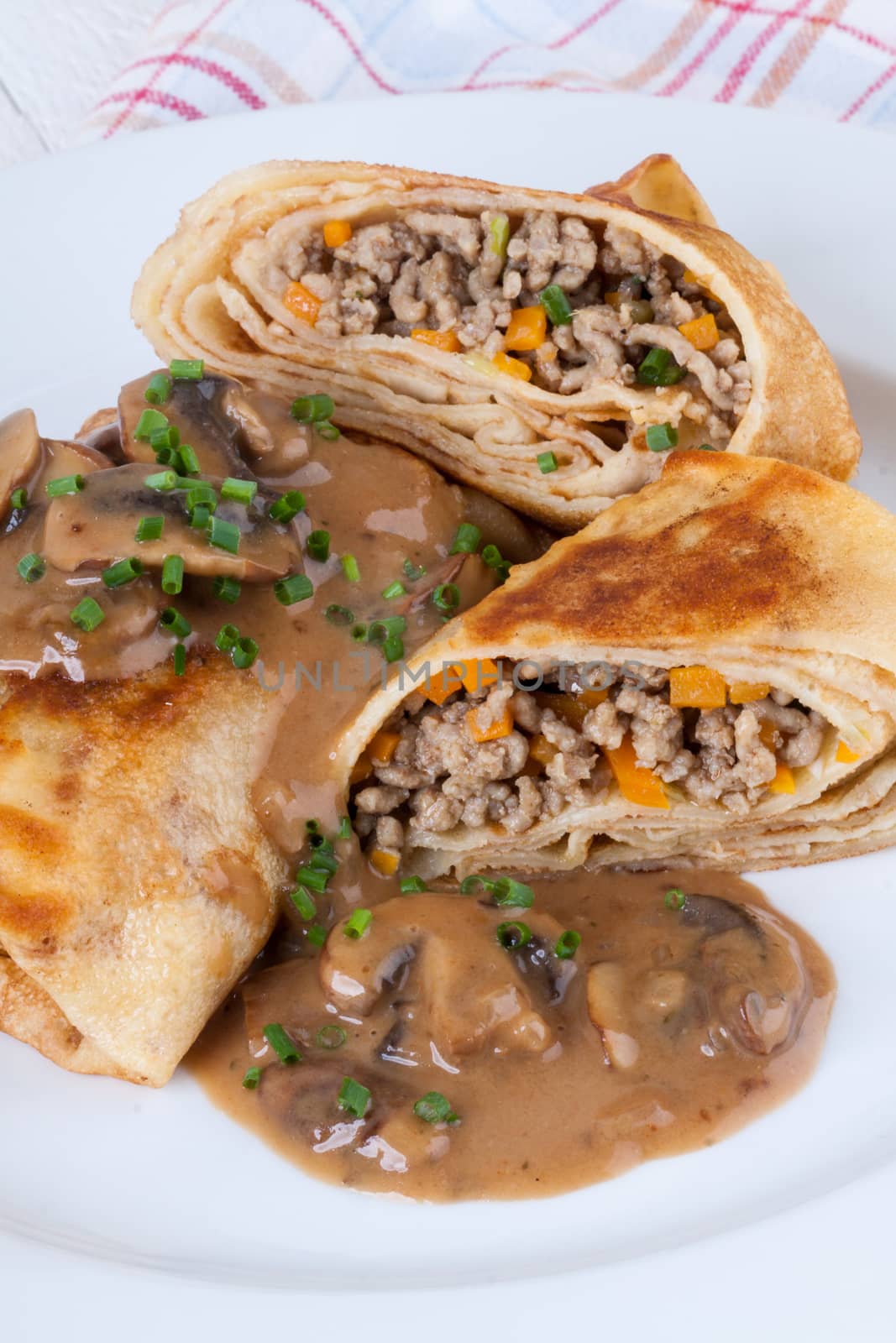 Savory mince pancakes or tortillas cut open to show the ground or minced meat and vegetable filling in a rich tasty gravy