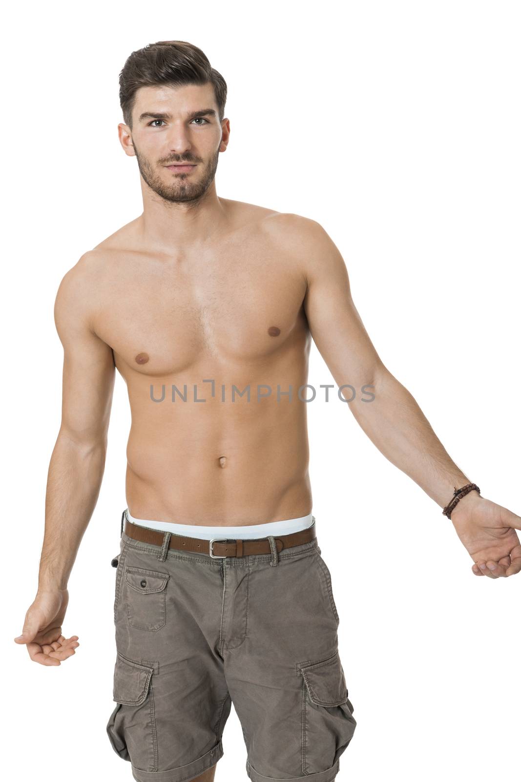 Handsome shirtless naked bearded young man standing looking intently at the camera with his hand to his chin in a sensual sexy pose, isolated on white