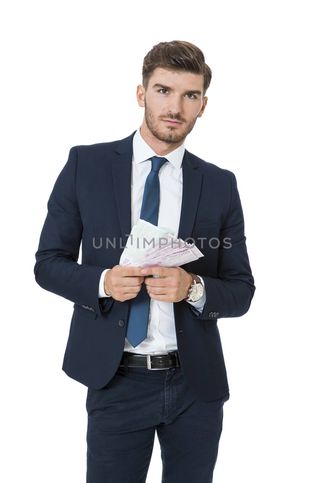 Wealthy successful stylish young businessman burning money from a handful of euro banknotes with a happy smile showing off his affluence, isolated on white