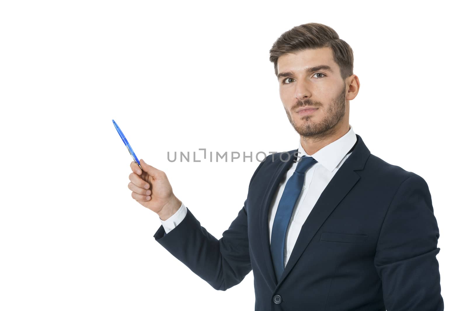 Stylish young businessman doing a presentation, making a selection or showing something pointing to the left of the frame with a pen in his hand as he stands sideways to the camera, isolated on white