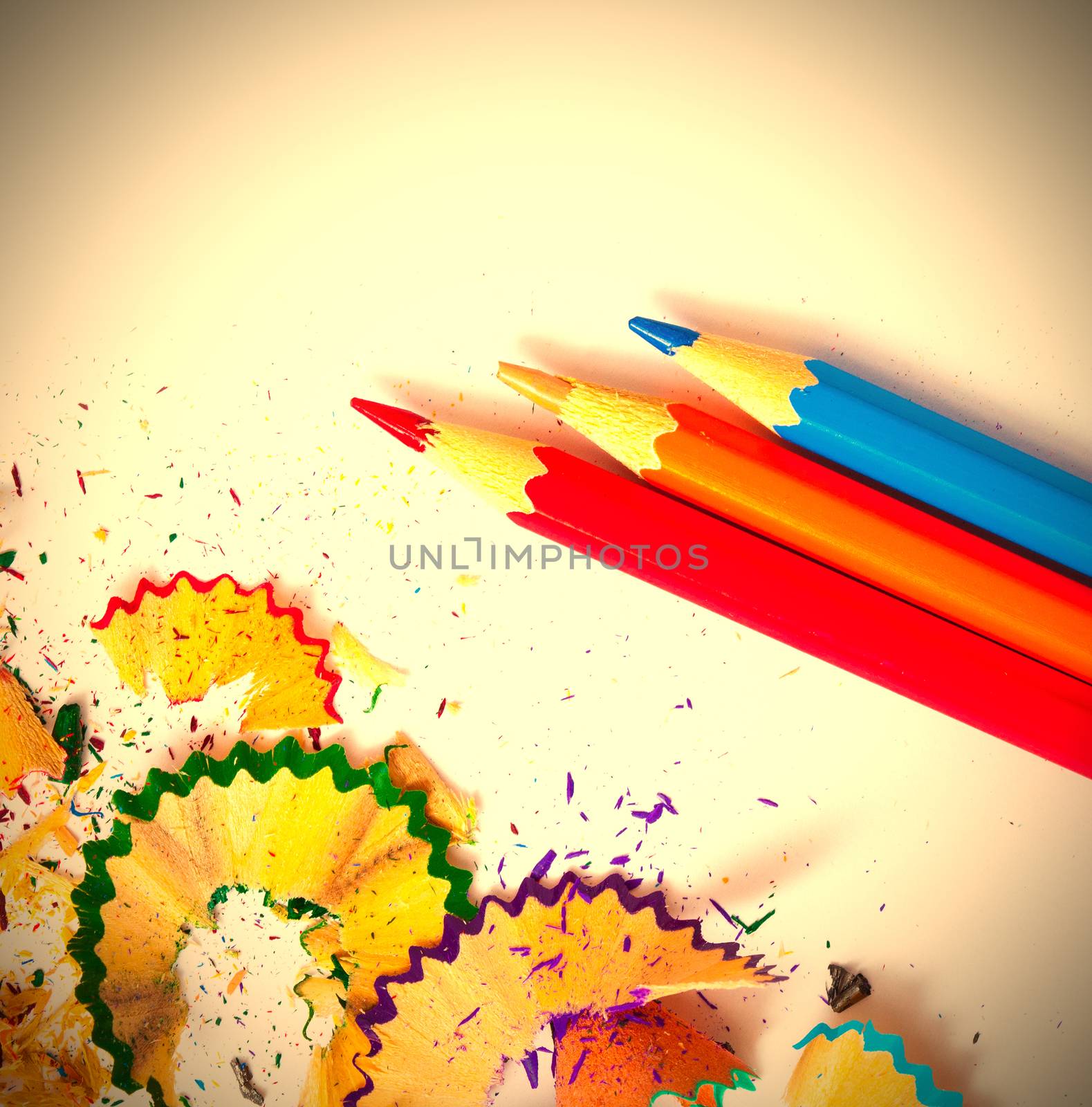 three colored pencils and shavings on white background with copy space. instagram image retro style