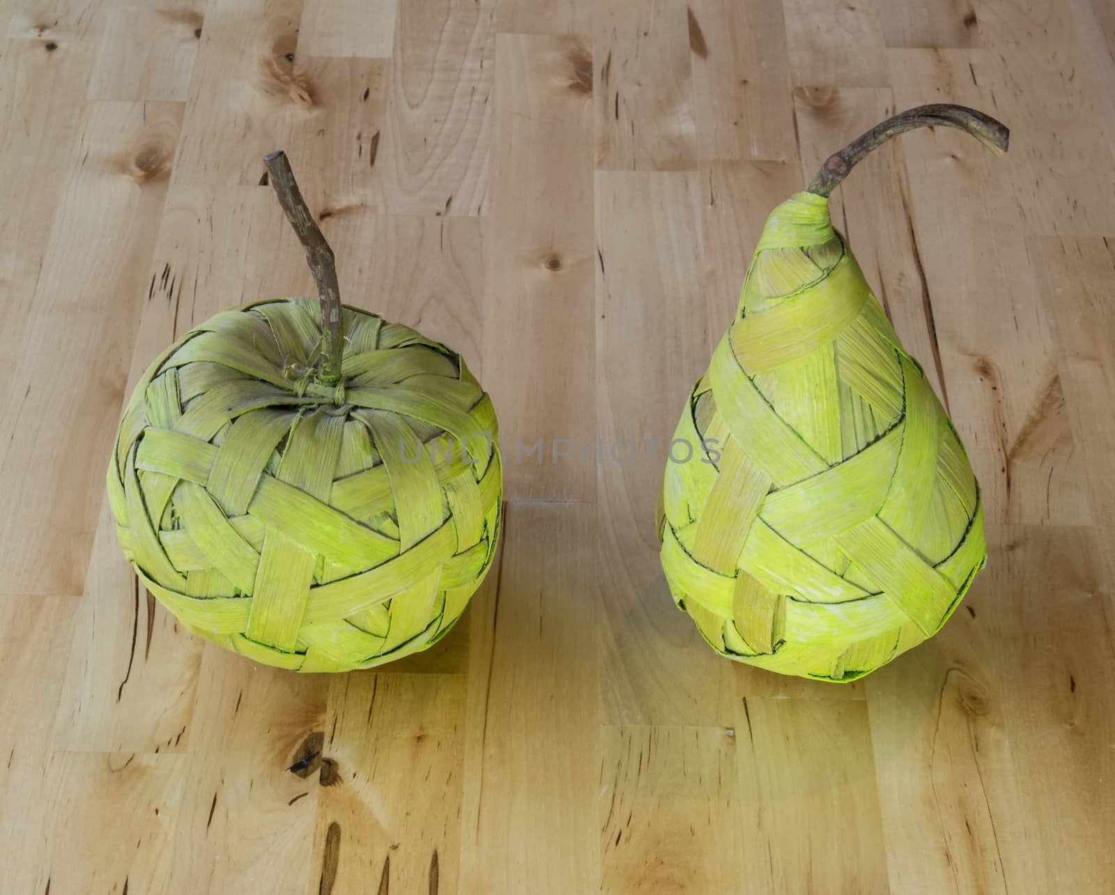 Green pear and apple made from bast fibre laying on the wooden table