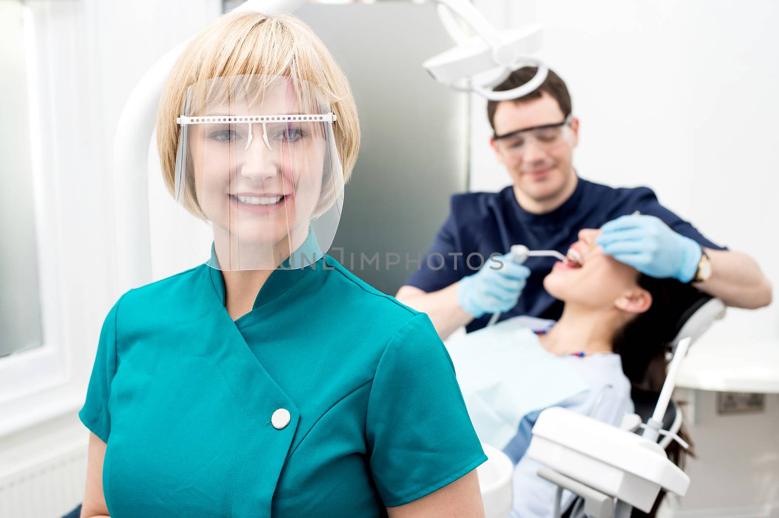 Male dentist with patient, in clinic. by stockyimages