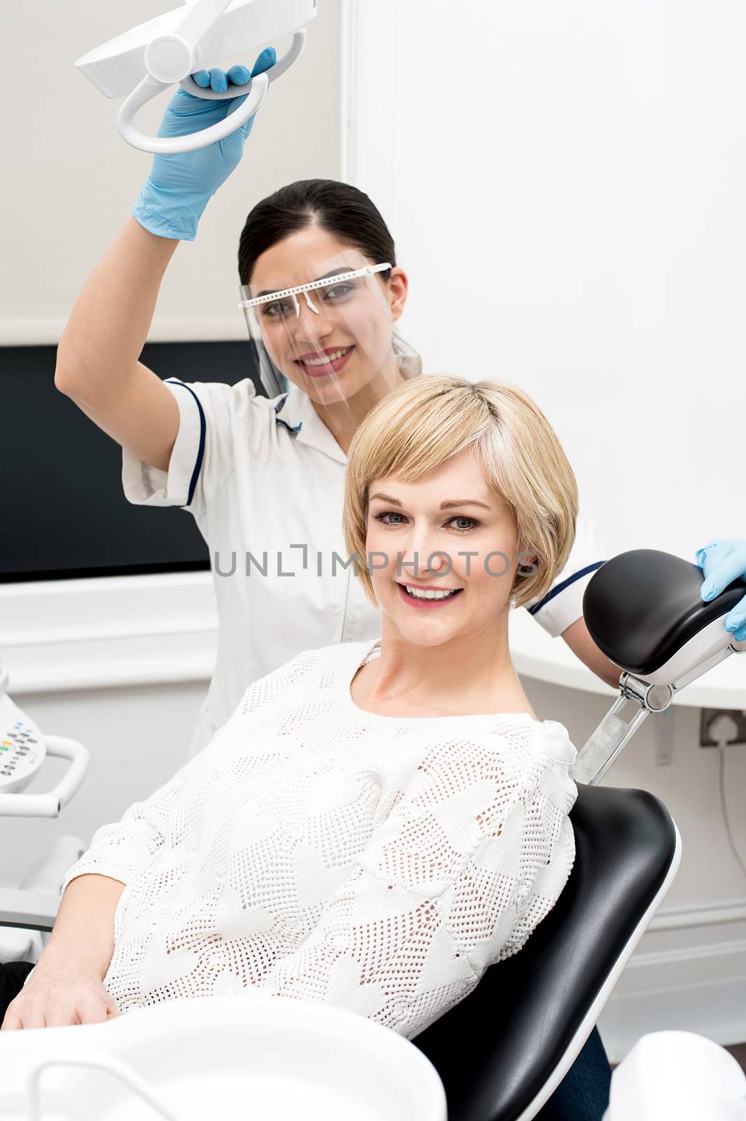 Dentist assistant and female patient looking at camera