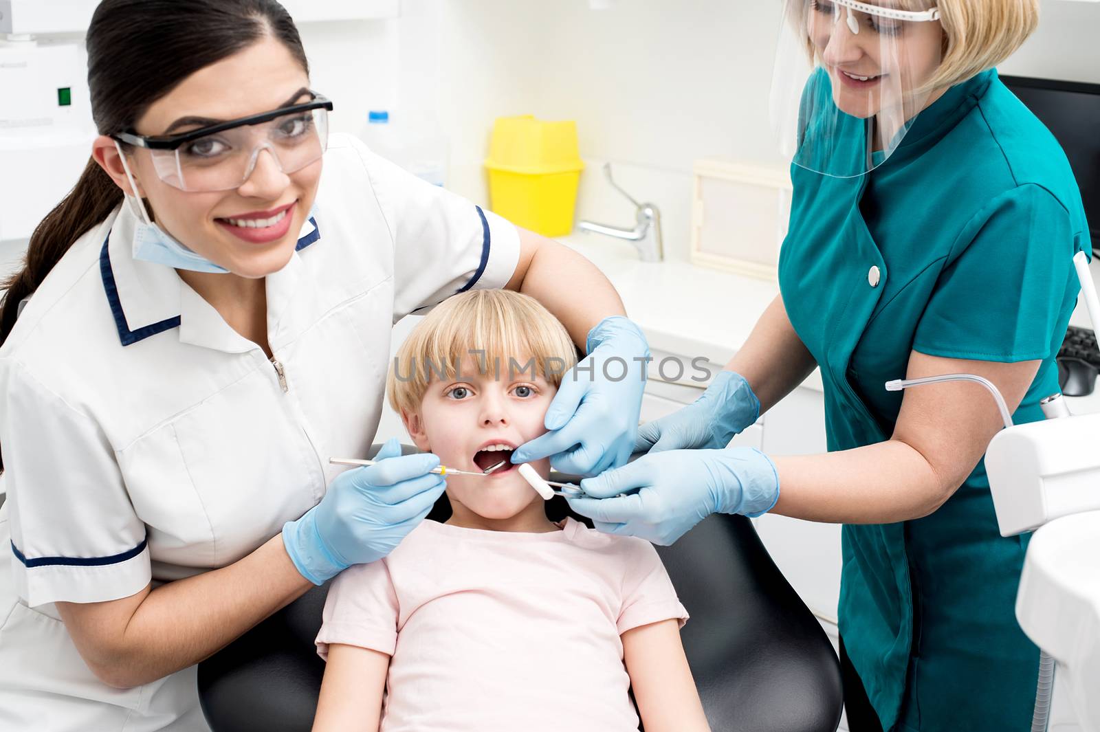Female dentist examine child patient by stockyimages