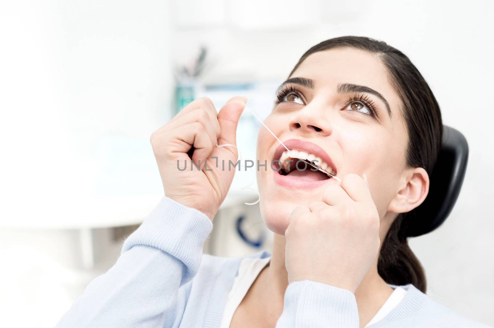 Woman cleaning her teeth with dental floss