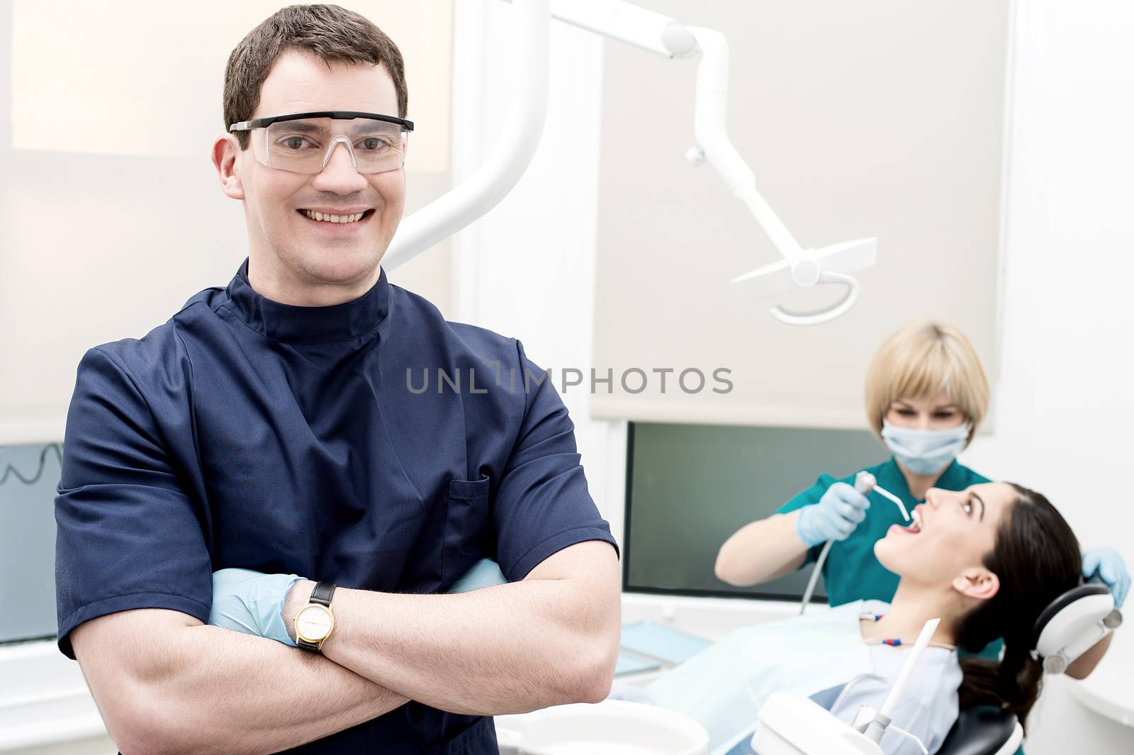 Male dentist, assistant and patient at dental clinic