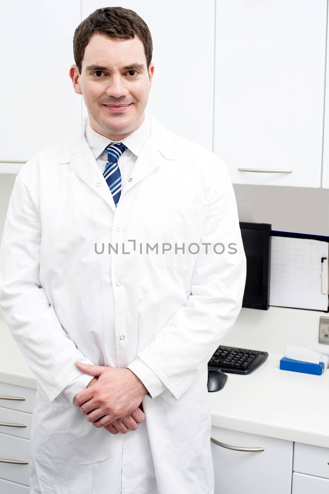 Happy male dentist posing at dental clinic
