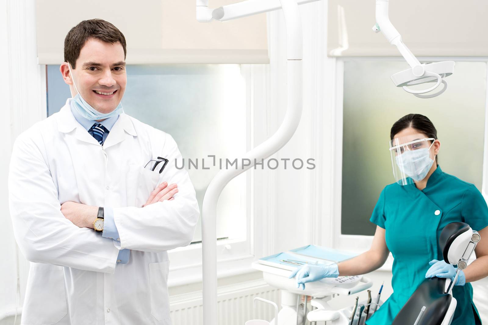 Confident dentist his female assistant posing behind