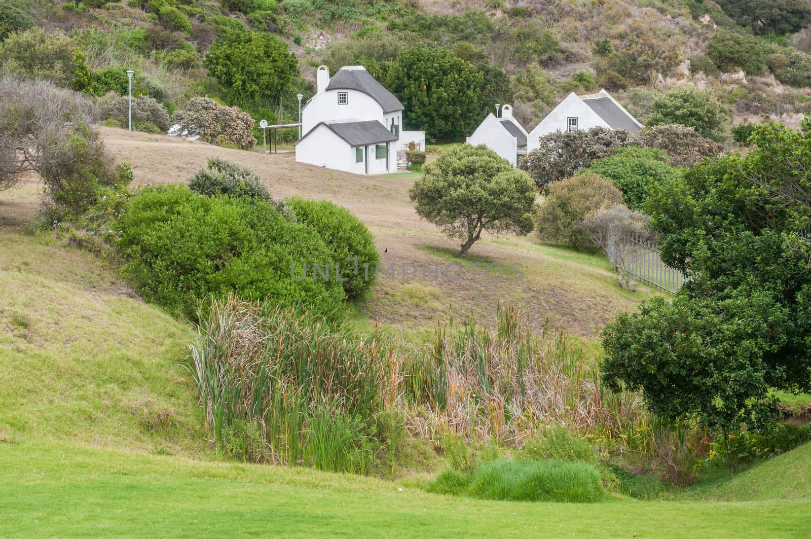MOSSELBAY, SOUTH AFRICA - DECEMBER 30, 2014:  The fountain at the Dias Museum which supplied early seafarers with water and the Munrohoek Cottages, built around 1830