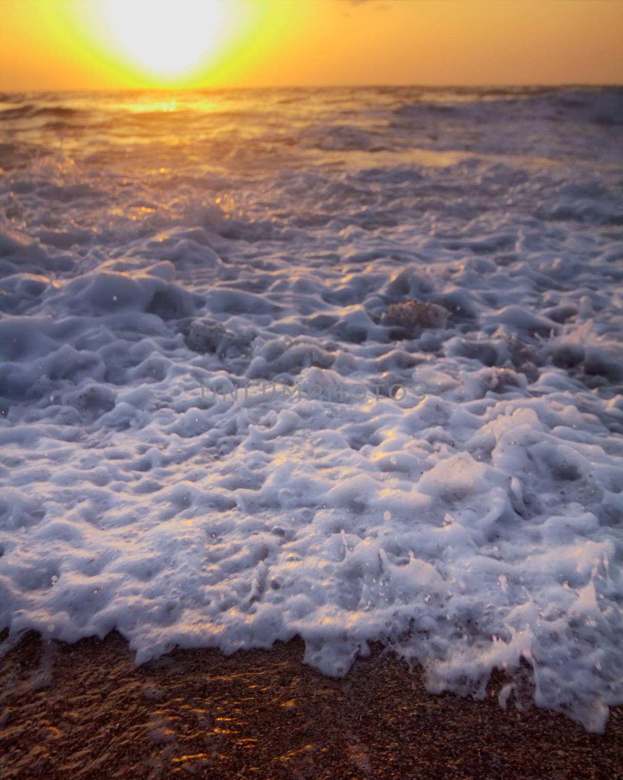 Gentle warm sea on backdrop of enchanting sunset. Foamy surf. Mediterranean sea.