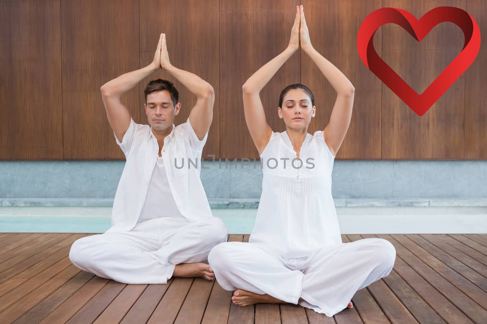 Attractive couple in white sitting in lotus pose with hands together against heart