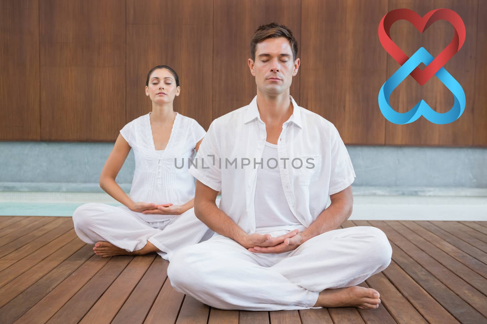 Peaceful couple in white sitting in lotus pose together against linking hearts