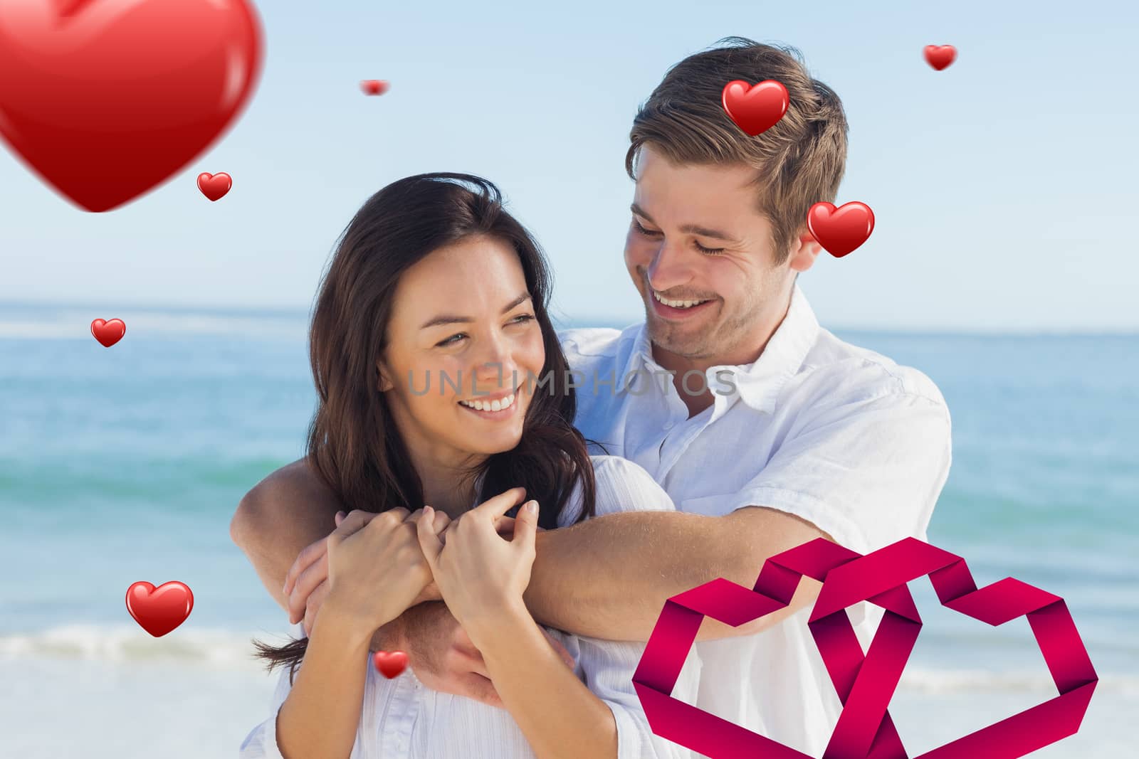 Cheerful couple relaxing on the beach during summer against linking hearts