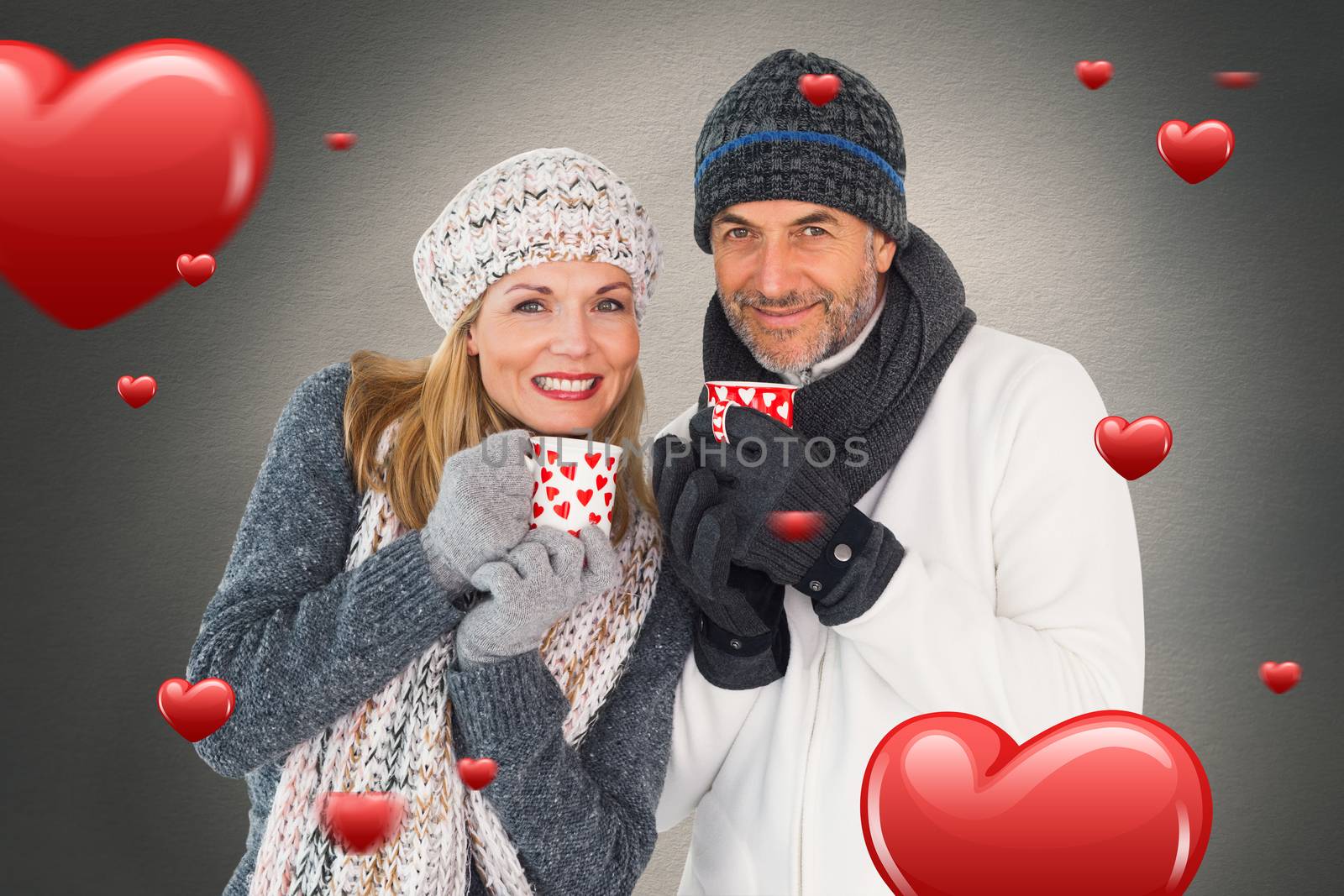 Happy couple in winter fashion holding mugs against white background with vignette