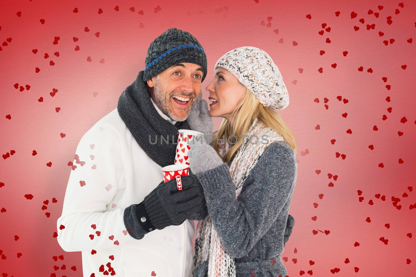 Happy couple in winter fashion holding mugs against red vignette