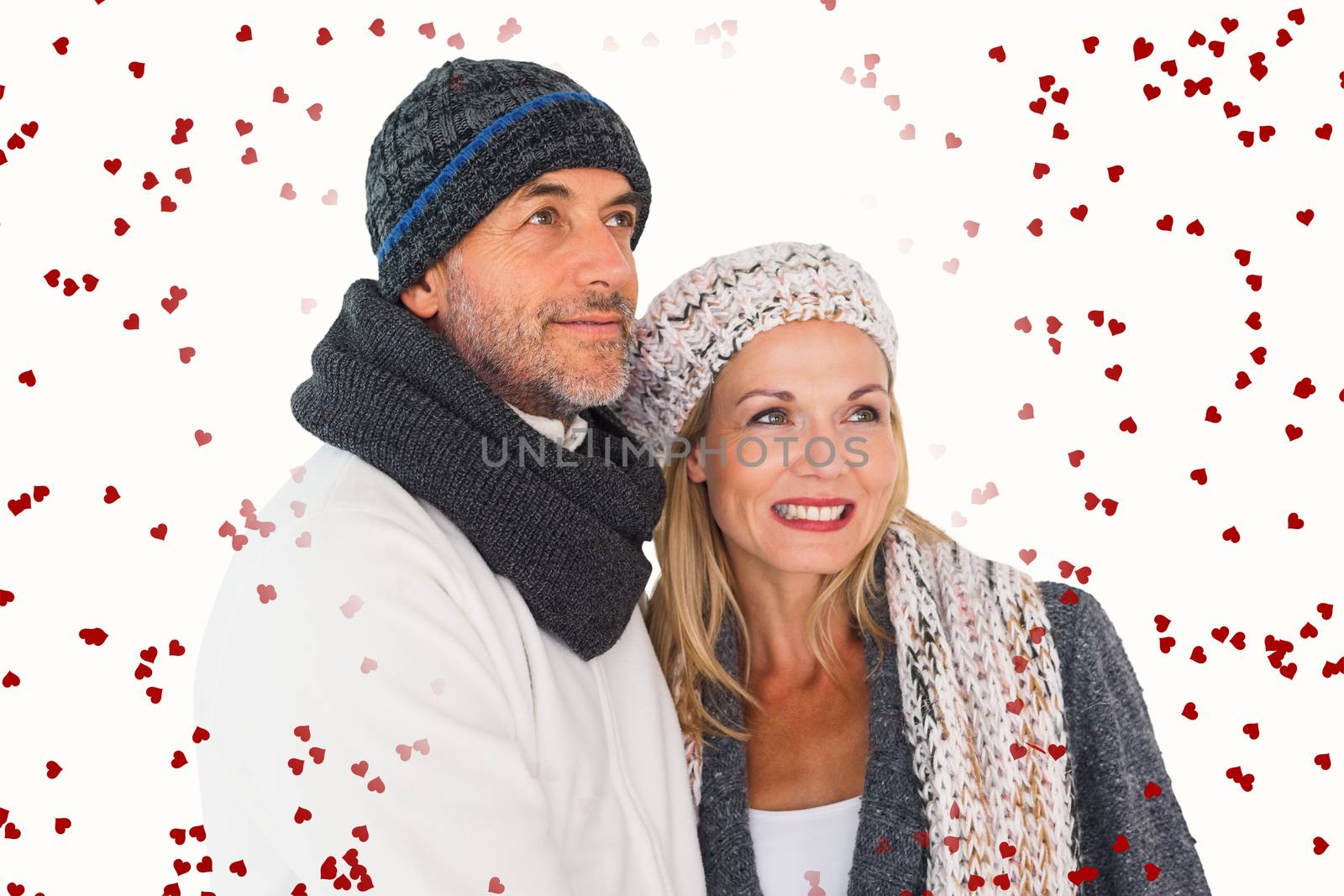 Happy couple in winter fashion embracing against red love hearts