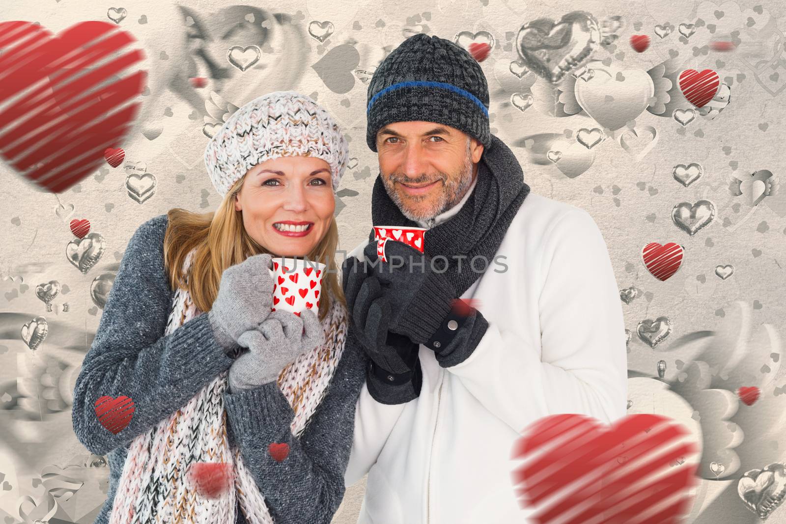 Happy couple in winter fashion holding mugs against grey valentines heart pattern