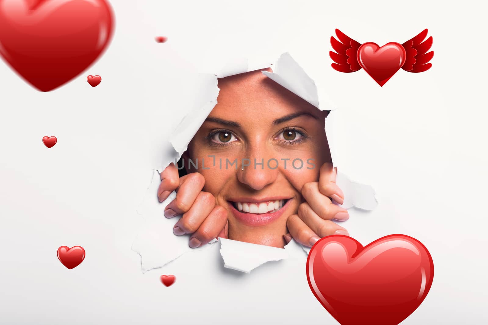 Young woman looking through paper rip against hearts