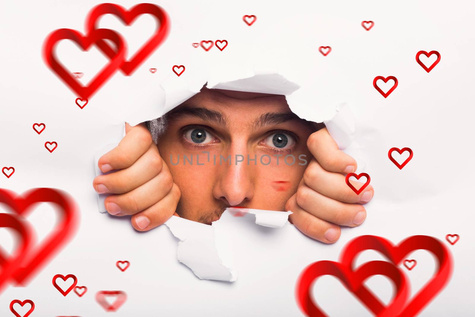 Young man looking through paper rip against hearts