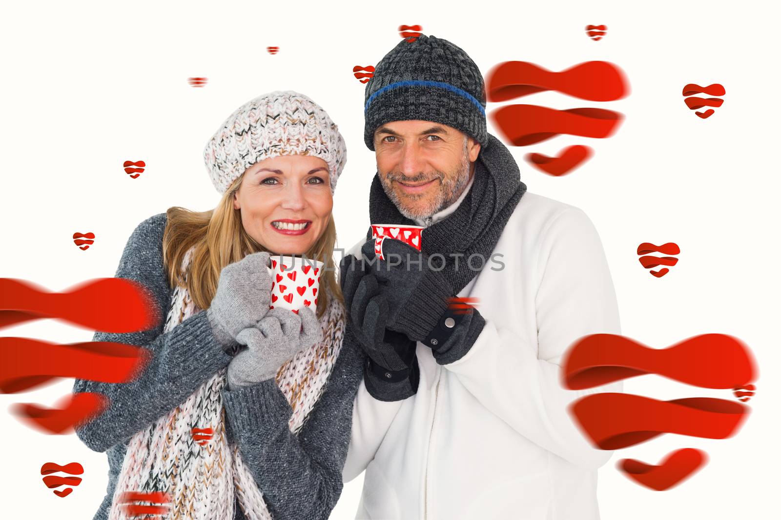 Happy couple in winter fashion holding mugs against hearts