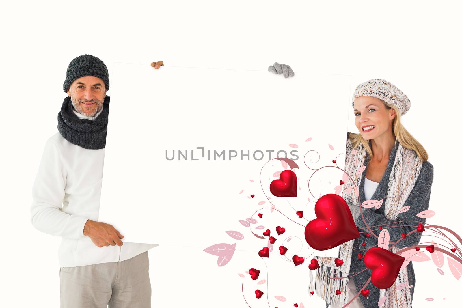 Smiling couple in winter fashion holding poster against valentines heart design