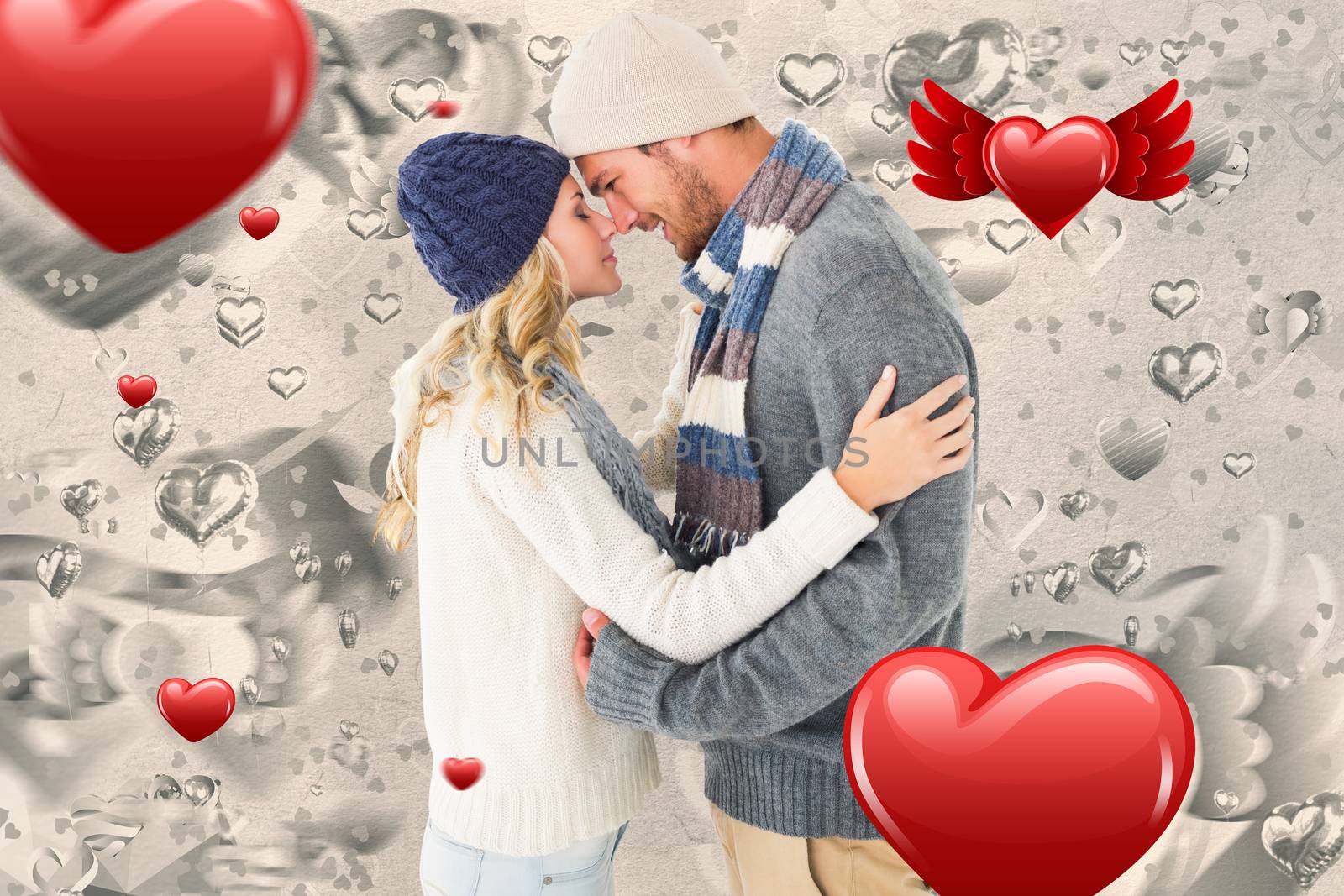 Attractive couple in winter fashion hugging against grey valentines heart pattern