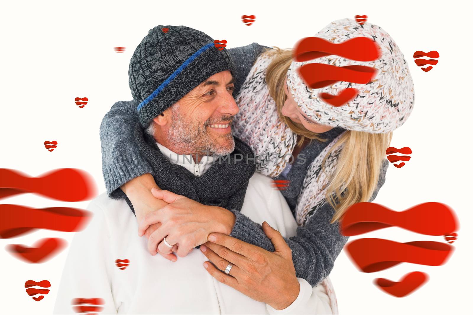 Happy couple in winter fashion embracing against hearts